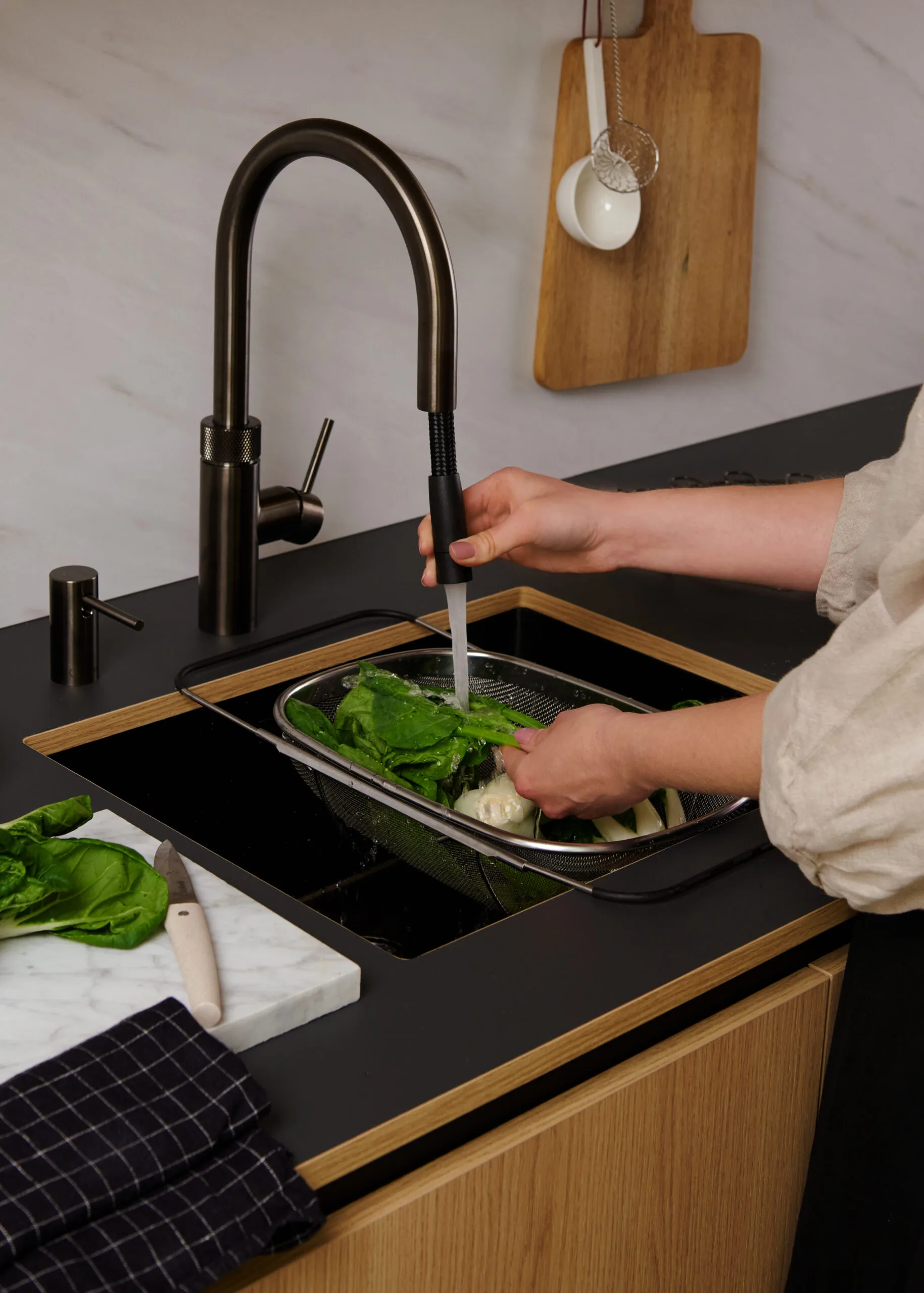 Quooker Flex boiling water tap in gunmetal black with pull-out hose rinsing vegetables at a kitchen sink
